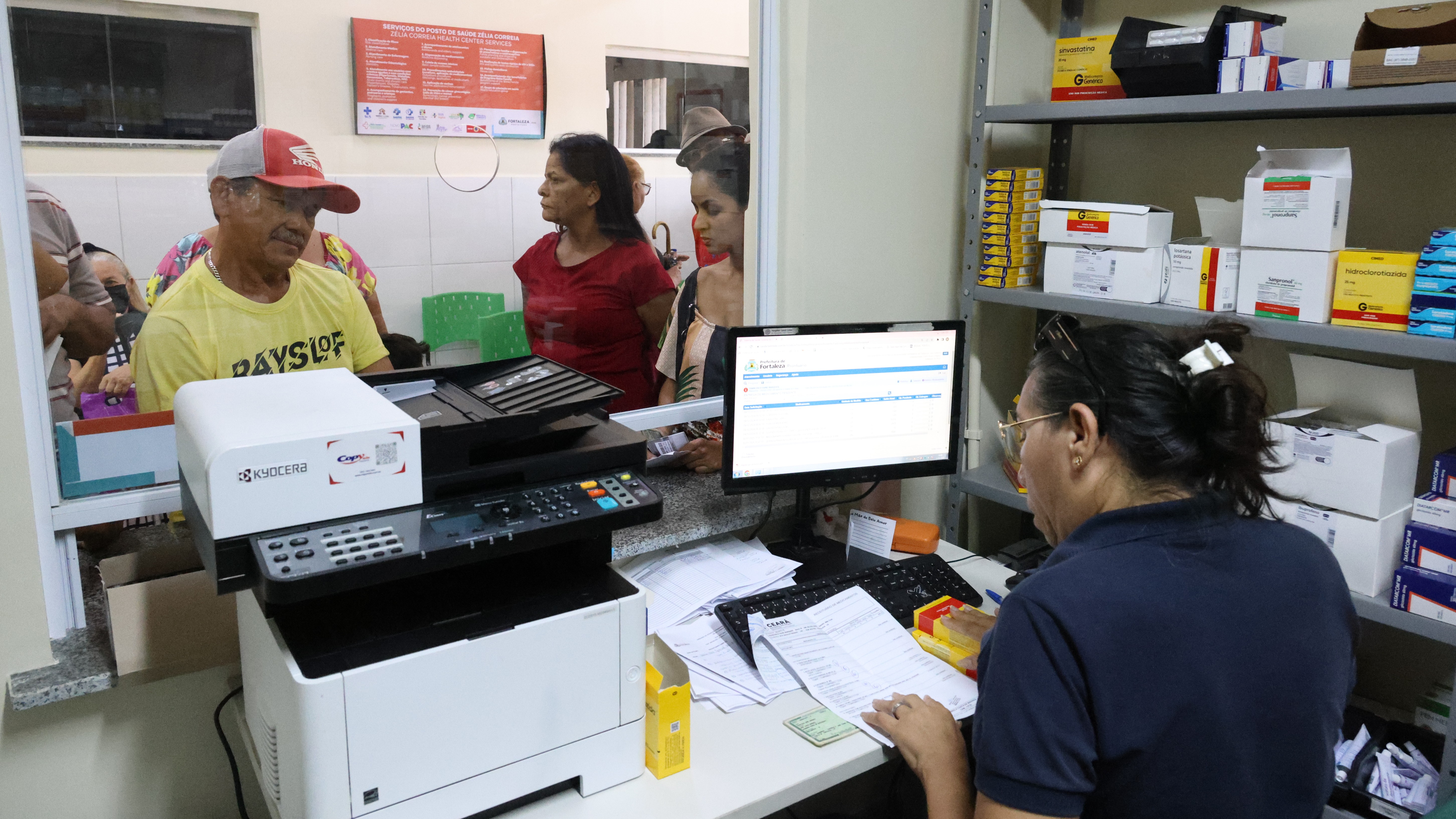 a imagem mostra uma atendente da farmácia no balcão e um senhor sendo atendido